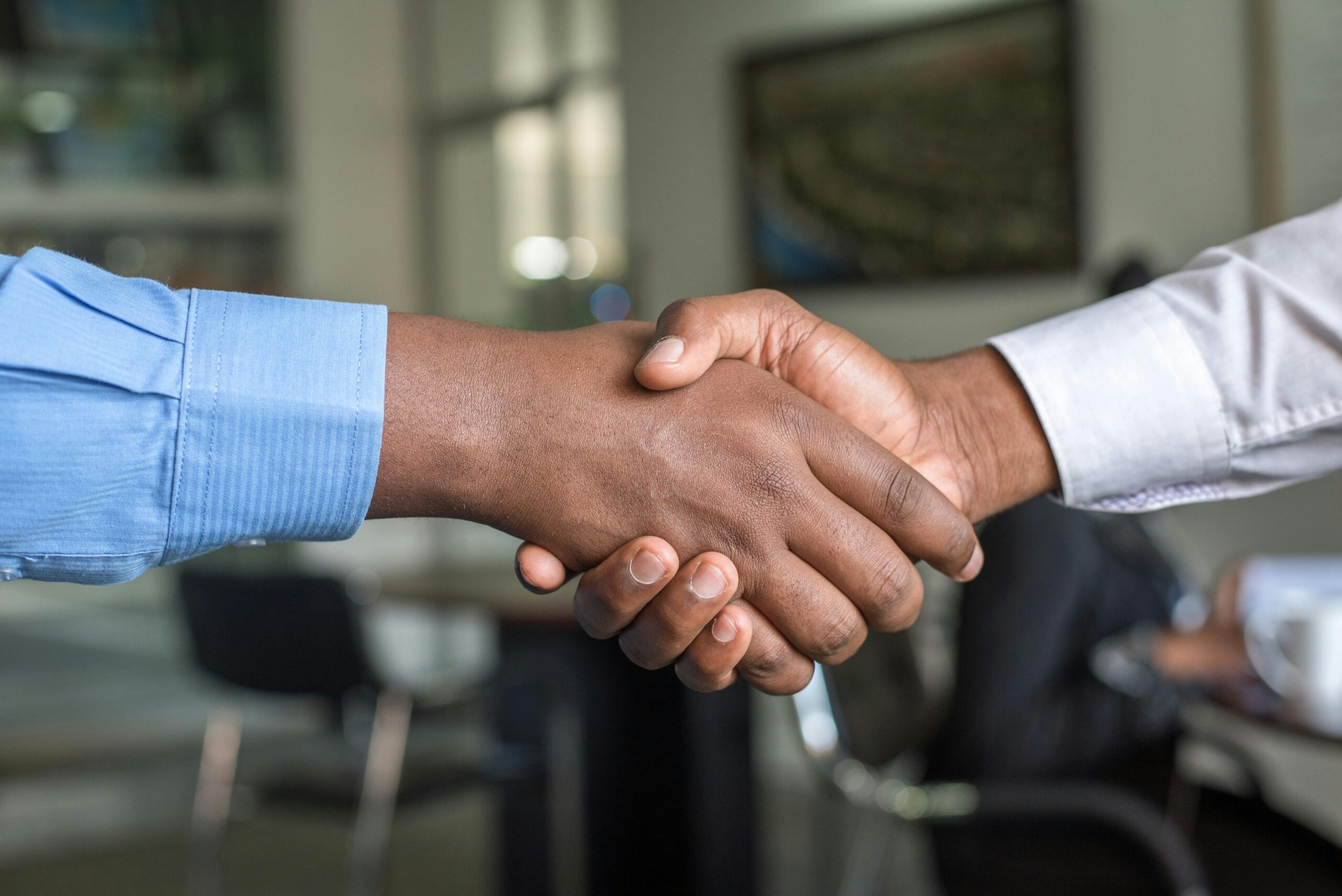 Close-up of two men's handshake symbolizing agreement in an office.