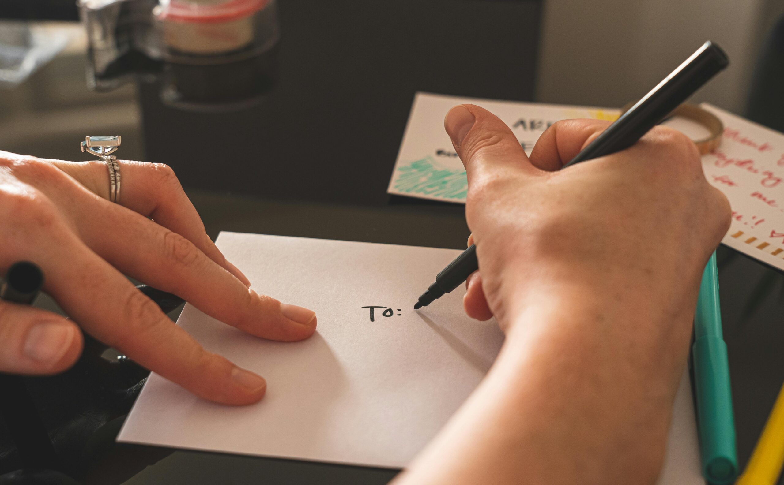 Hands writing on an envelope with marker, emphasizing handwritten correspondence.